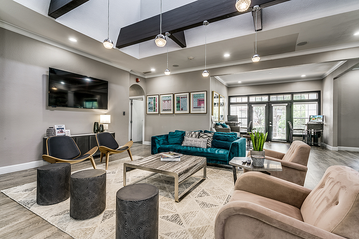 Modern clubhouse featuring stylish furniture, elegant lighting, and a vibrant teal sofa, perfect for relaxation and socializing.