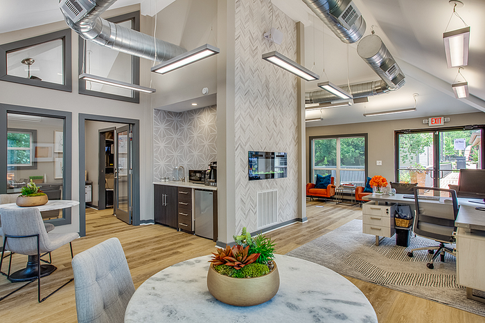 Modern, airy clubhouse with sleek open-concept living area, stylish decor, large windows, and contemporary furnishings.