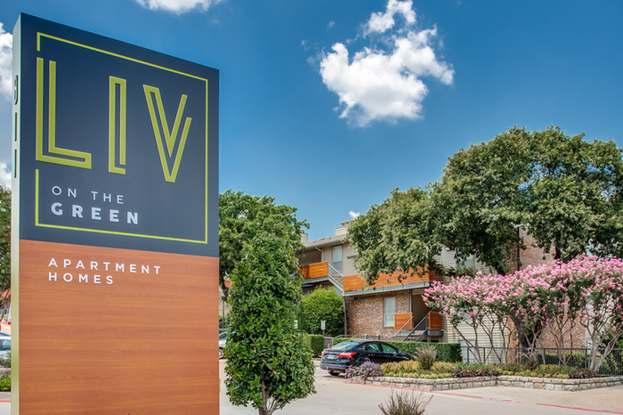 Inviting exterior of Liv on the Green apartment homes, surrounded by lush greenery and vibrant flowers.