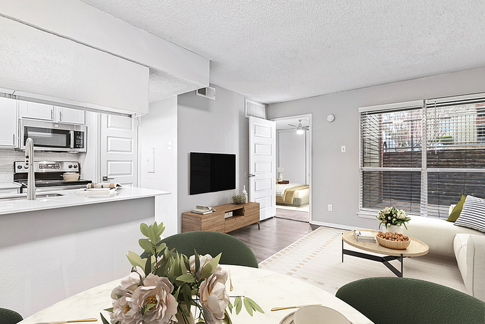 Modern open-concept living space featuring a sleek kitchen with stainless steel appliances, cozy living room, and abundant natural light from large windows.