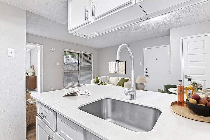 Bright and modern kitchen with sleek countertops and open living area perfect for entertaining, showcasing chic decor and natural light.