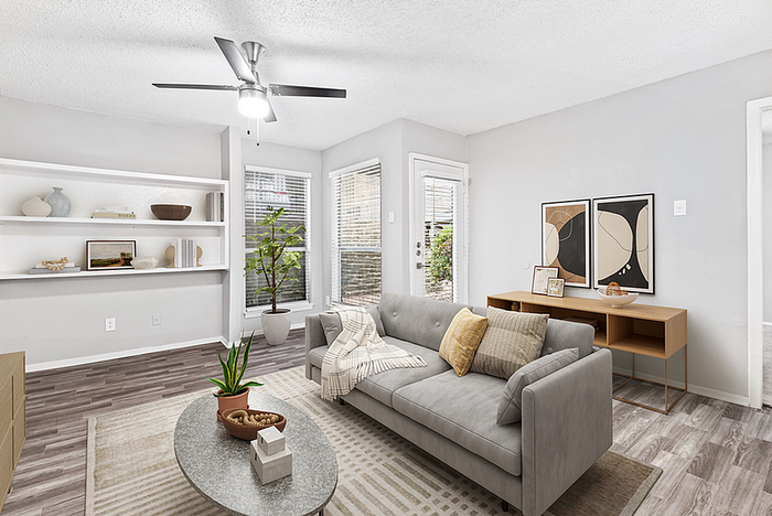 Contemporary living room with elegant gray sofa, chic decor, vibrant potted plants, and large windows providing ample natural light.