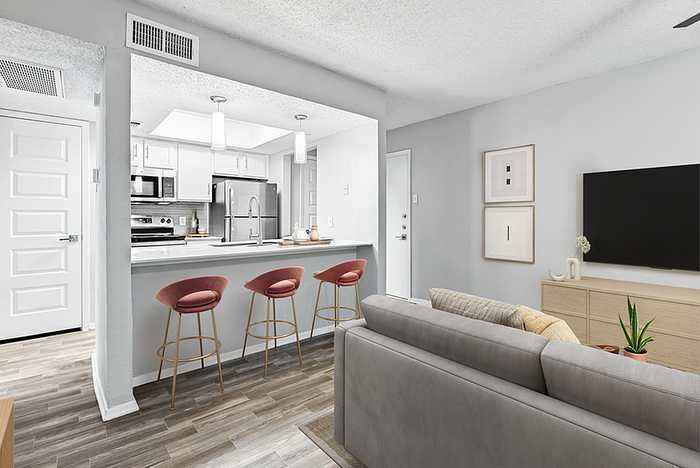 Contemporary open-concept living space with a modern kitchen, stylish bar stools, and cozy living room, ideal for urban living.