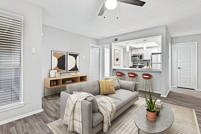 Modern open-plan living area with stylish decor featuring a cozy sofa, elegant coffee table, and sleek kitchen with stainless steel appliances and chic bar seating.