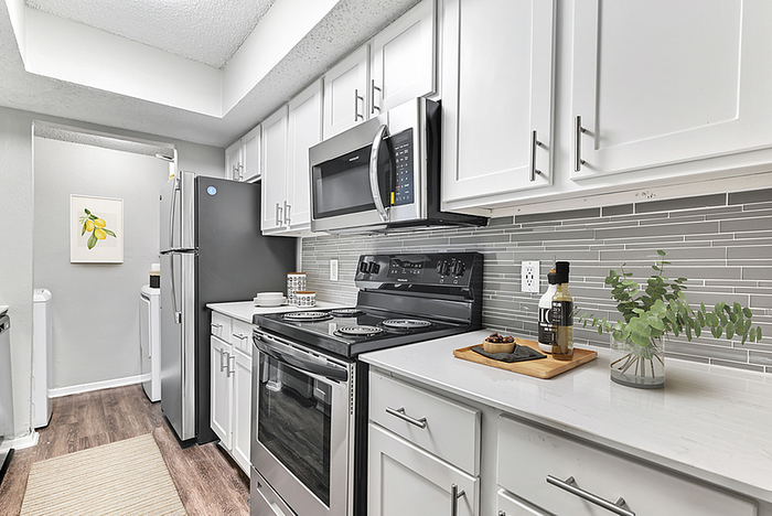Modern kitchen with stainless steel appliances, sleek white cabinets, and stylish gray backsplash.