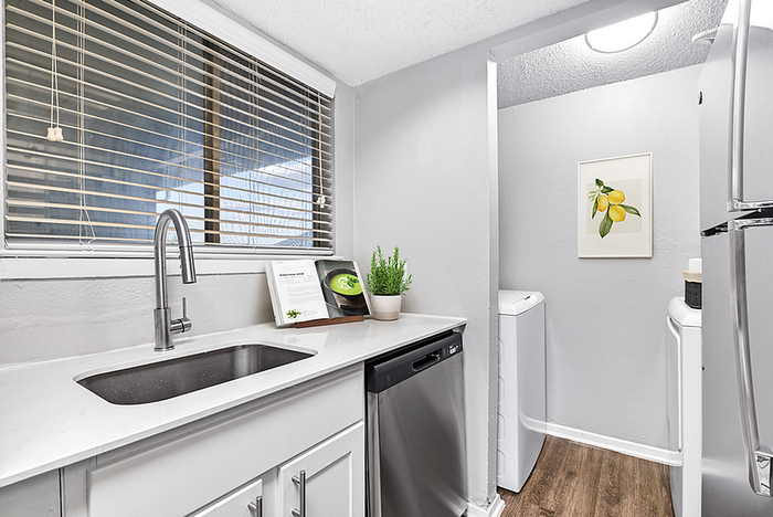 Modern kitchen with sleek stainless steel appliances, elegant white countertops, and a vibrant lemon artwork on the wall.