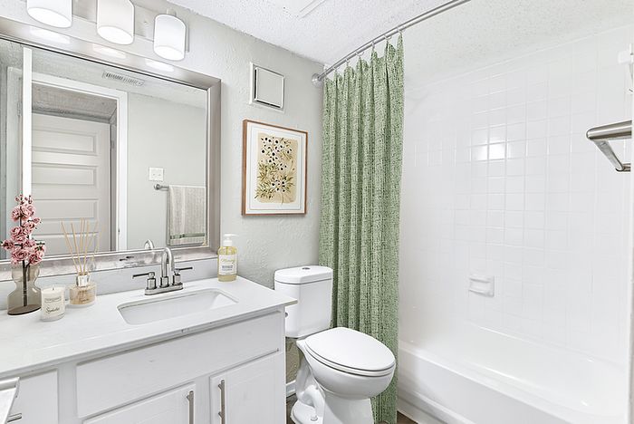 Bright and elegant bathroom featuring a modern vanity, stylish lighting, and soothing green shower curtains.