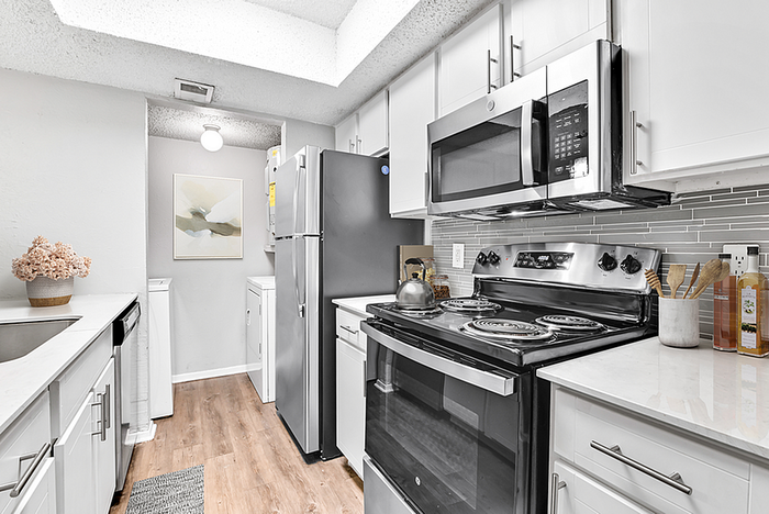 Modern kitchen with sleek stainless steel appliances, elegant white cabinetry, and a stylish backsplash, exuding contemporary charm.