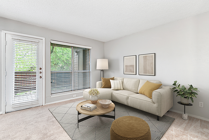 Bright and inviting living room with modern decor, cozy beige sofa, elegant coffee table, and natural light from large windows and glass door.