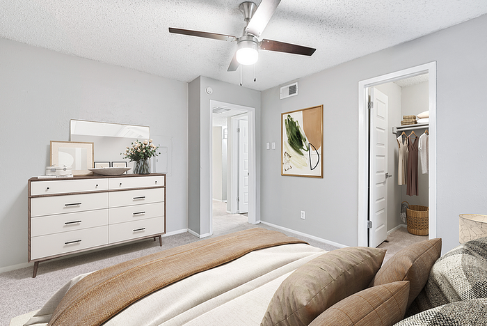 Bright and inviting bedroom featuring a stylish dresser, cozy bed with plush pillows, and a convenient walk-in closet.