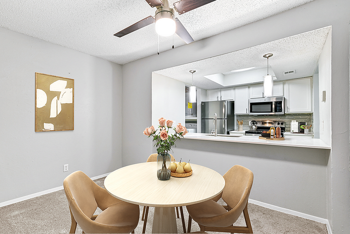 Charming dining area with elegant wood table and plush chairs, seamlessly connected to a modern kitchen with sleek appliances and stylish decor.