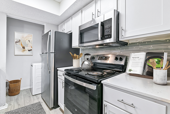 Modern kitchen showcasing sleek stainless steel appliances, elegant white cabinetry, and a chic backsplash for a stylish culinary space.