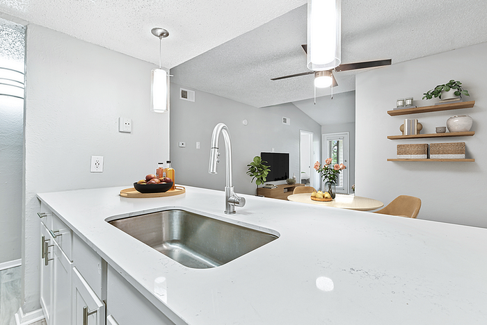Elegant modern kitchen with white countertops, open dining area, and stylish decor, creating a welcoming and airy atmosphere.