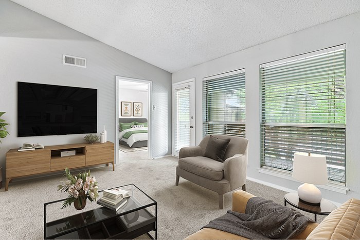 Bright and inviting living room with large windows, plush seating, and a modern media console, leading to a cozy bedroom with stylish decor.