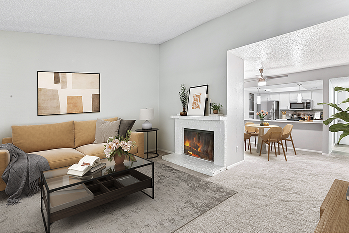 Inviting living space with cozy sofa, elegant fireplace, and open-concept kitchen and dining area, stylishly designed for comfort and sophistication.