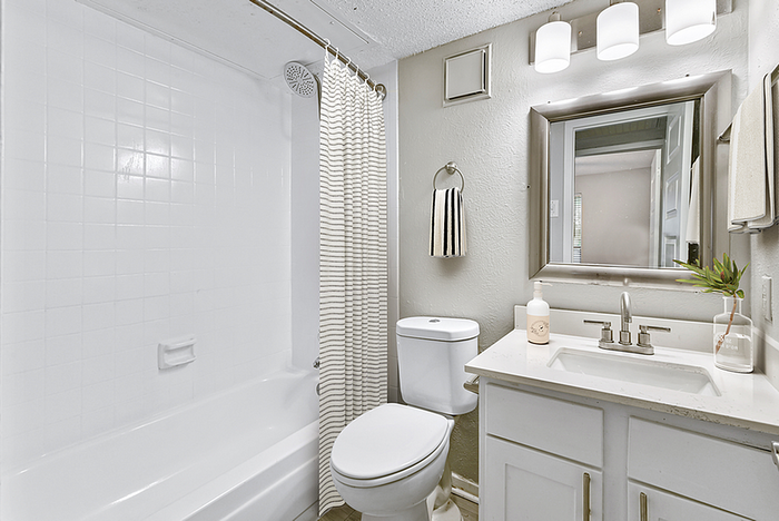 Modern bathroom with sleek white tiles, elegant vanity, and chic lighting, creating a bright and inviting atmosphere.