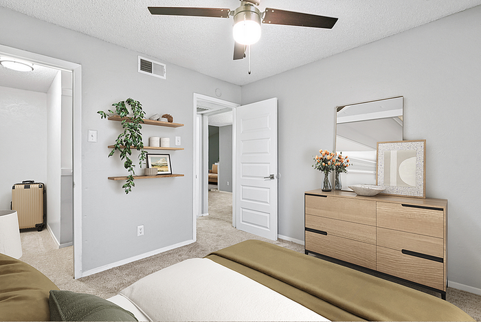 Inviting bedroom with modern decor, featuring a sleek dresser, wall art, and lush greenery for a cozy ambiance.