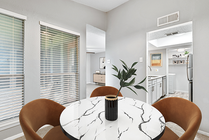 Bright dining area with modern marble table and cozy leather chairs, adjacent to sleek kitchen featuring elegant cabinetry and stainless steel appliances.