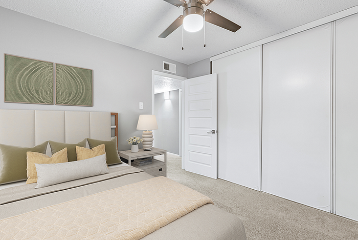 Elegant bedroom with chic neutral decor, plush carpeting, and a modern ceiling fan enhancing comfort and style.