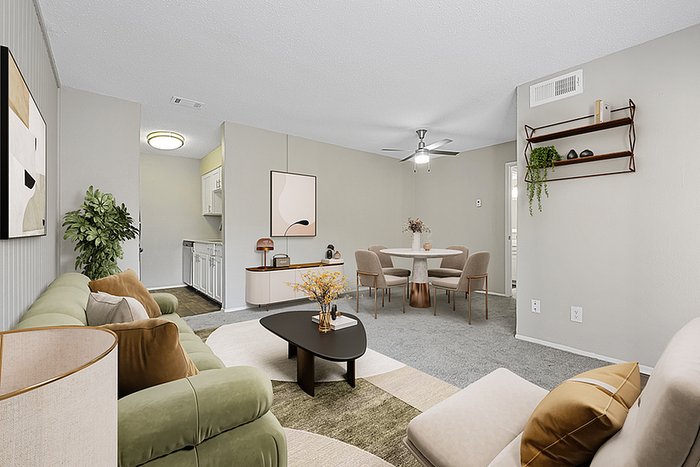 Inviting living area with stylish decor, featuring a plush green sofa, modern coffee table, and open dining space, perfect for entertaining in a cozy apartment setting.