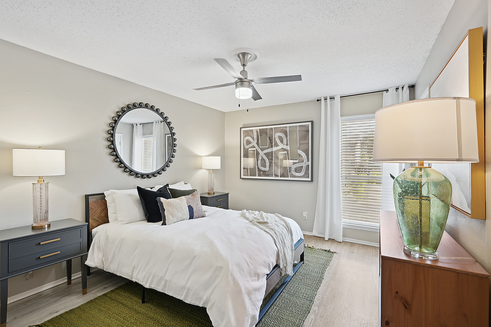 Elegant bedroom with modern decor, featuring a plush bed, stylish lamps, and a large decorative mirror.