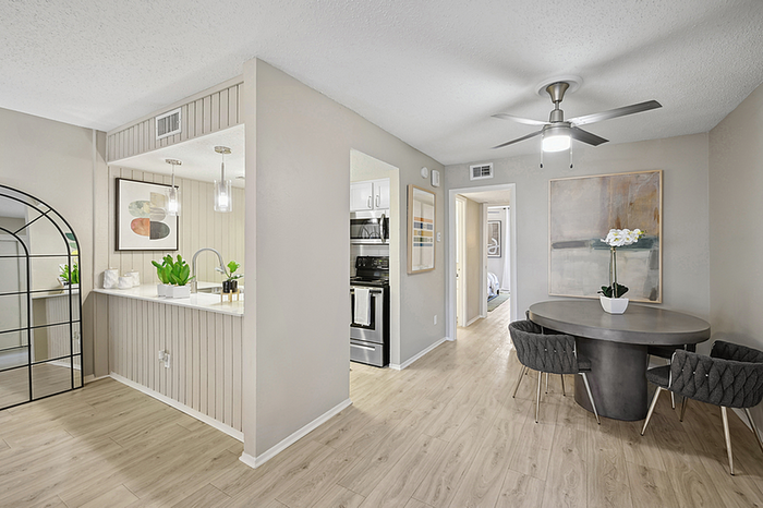 Bright modern apartment interior with open kitchen, stylish dining area, and sleek wood flooring.