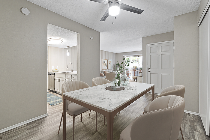 Elegant apartment dining area with a chic marble table, plush upholstered chairs, and open access to a modern kitchen and cozy living room.