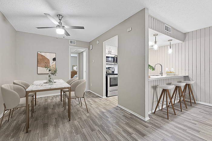 Chic apartment dining area with a modern marble table, elegant chairs, and a stylish open-plan kitchen featuring a breakfast bar and contemporary lighting.
