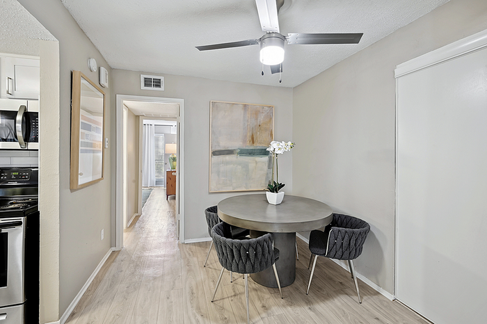Chic dining area with modern round table, plush chairs, and elegant lighting, adjacent to a stylish kitchen, showcasing contemporary apartment living.