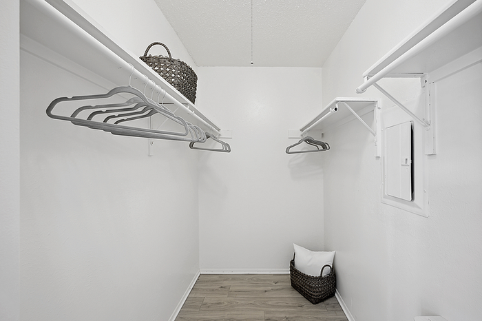 Spacious and modern walk-in closet featuring sleek shelving, a stylish wicker basket, and ample storage space.