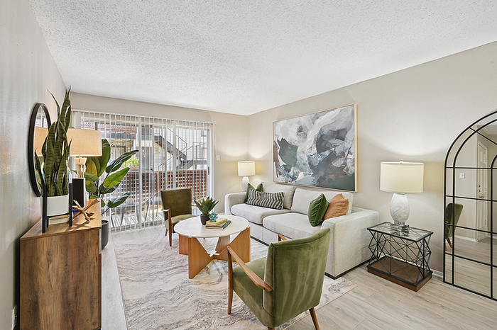 Inviting living room with modern decor, featuring a cozy sofa, elegant plants, and large windows flooding the space with natural light.