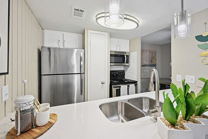Modern kitchen with sleek stainless steel appliances, elegant white cabinetry, and contemporary lighting, providing a sophisticated and inviting ambiance.