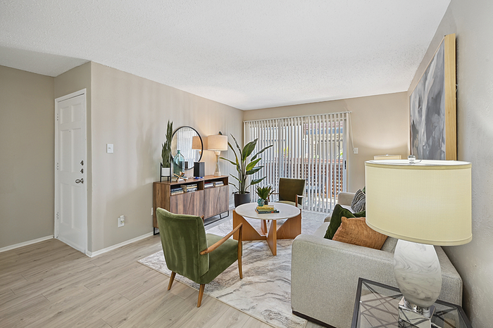 Bright and inviting living room with modern decor, featuring a cozy couch, stylish armchairs, large window with blinds, and elegant wood accents.