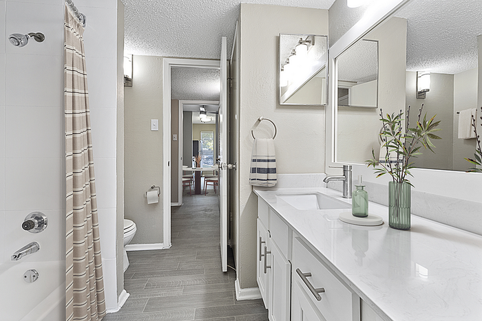 Modern bathroom with sleek white vanity, elegant decor, and a view into a bright dining area.