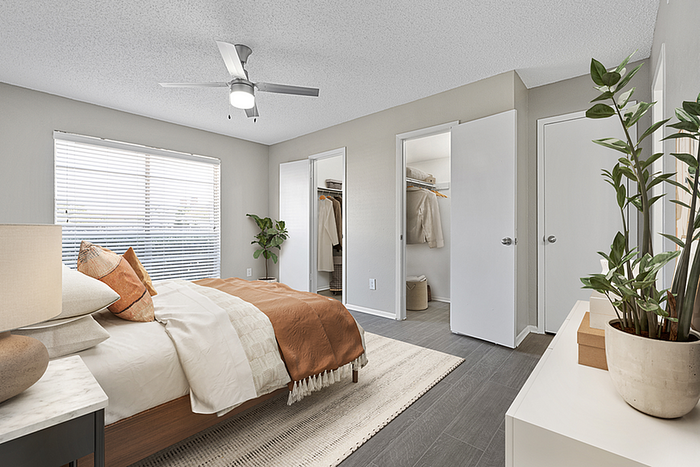 Bright and cozy bedroom with modern ceiling fan, large window, and ample closet space, perfect for comfort and style.
