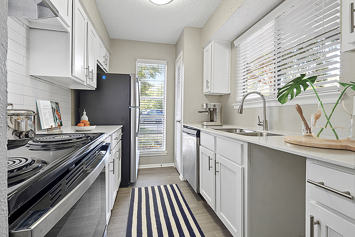 Bright, modern galley kitchen with sleek white cabinetry, stainless steel appliances, and ample natural light.