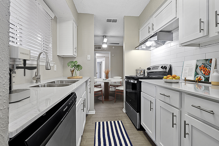 Sleek modern kitchen with white cabinets, stainless steel appliances, and a cozy dining area in the background.