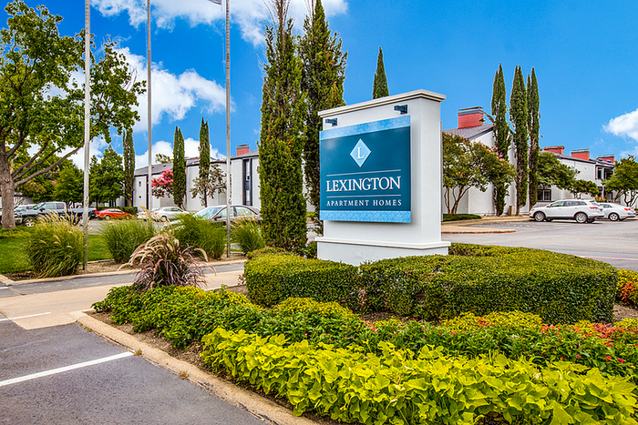 Inviting exterior view of Lexington Apartment Homes with lush landscaping and a clear blue sky.