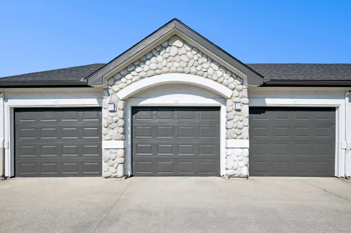Three private garage doors with stone accents at the apartment community.