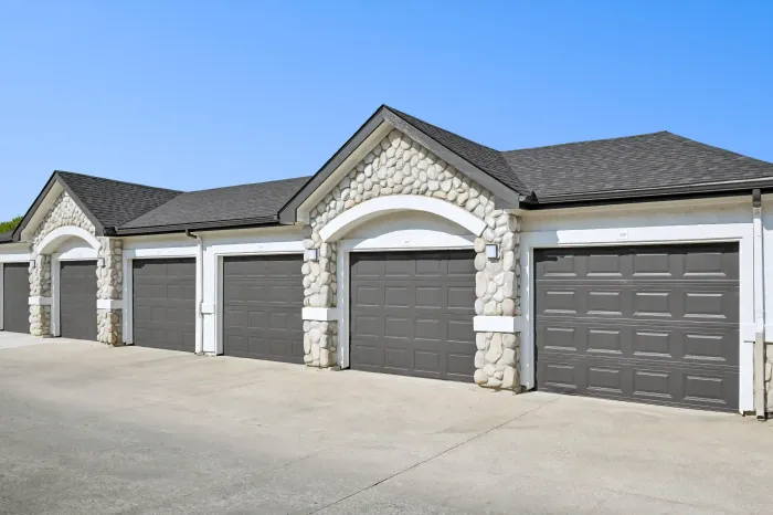 Row of private garages featuring dark doors and stone accents at the apartment community.