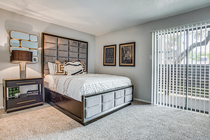 Elegant and spacious bedroom with plush bed, chic nightstand, modern decor, and large glass doors for ample natural light.