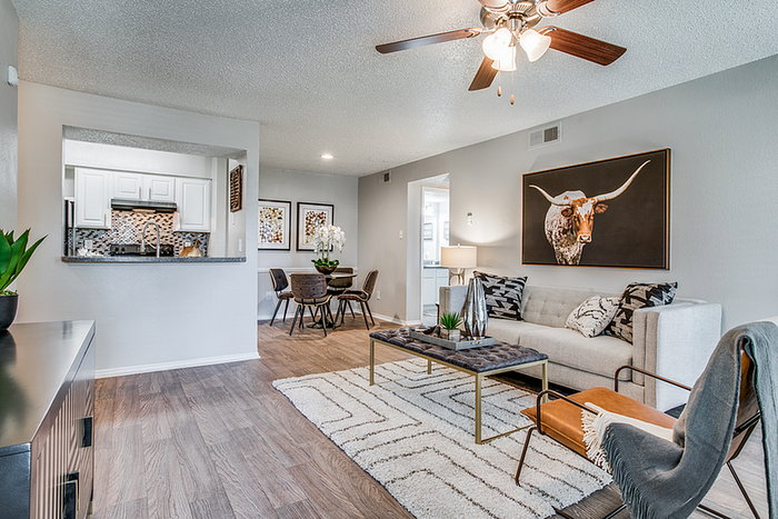Chic living room with modern decor, cozy seating, and an open-plan kitchen featuring stylish tile backsplash.
