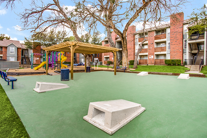 Inviting community space featuring a vibrant playground, shaded seating, and modern apartment buildings, ideal for families.