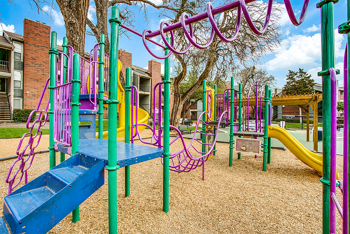 Vibrant playground with colorful slides and climbing structures surrounded by lush trees, perfect for family fun.
