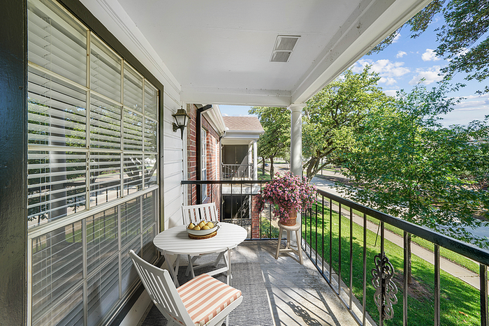 Charming balcony with a cozy seating area, vibrant potted flowers, and a scenic view of lush greenery.