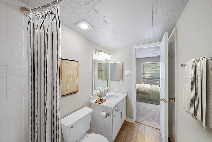 Charming bathroom with modern white fixtures, elegant lighting, and a view into a cozy bedroom, perfect for comfortable living.