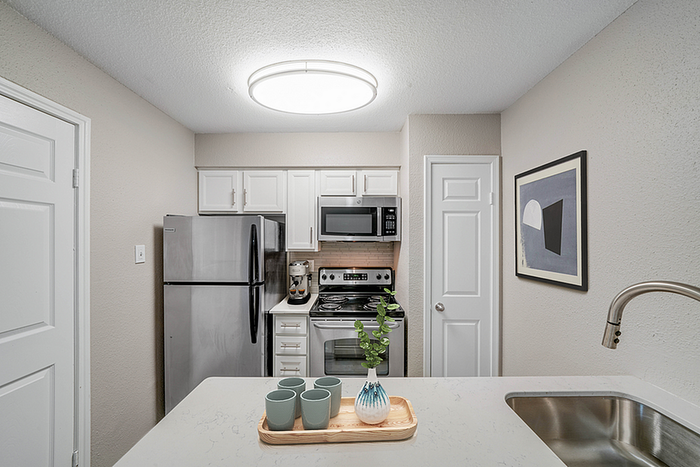 Modern kitchen with sleek stainless steel appliances, chic white cabinetry, and stylish countertops, adorned with minimalistic decor.