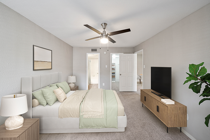Elegant bedroom with plush bedding, modern ceiling fan, and sleek furniture. Inviting, serene, and beautifully decorated, perfect for relaxation.
