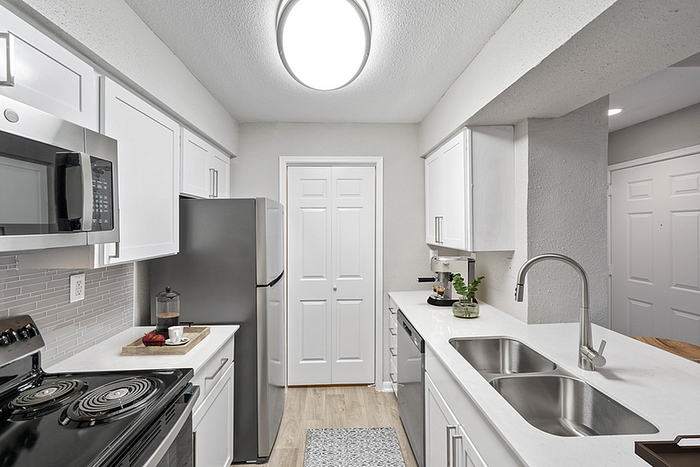 Bright and modern kitchen with sleek stainless steel appliances, white cabinetry, and elegant fixtures providing a chic and functional cooking space.