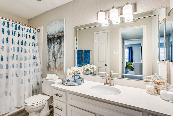 Elegant bathroom with modern fixtures, featuring a chic shower curtain, luxurious countertop, and vibrant wall art for a touch of style.